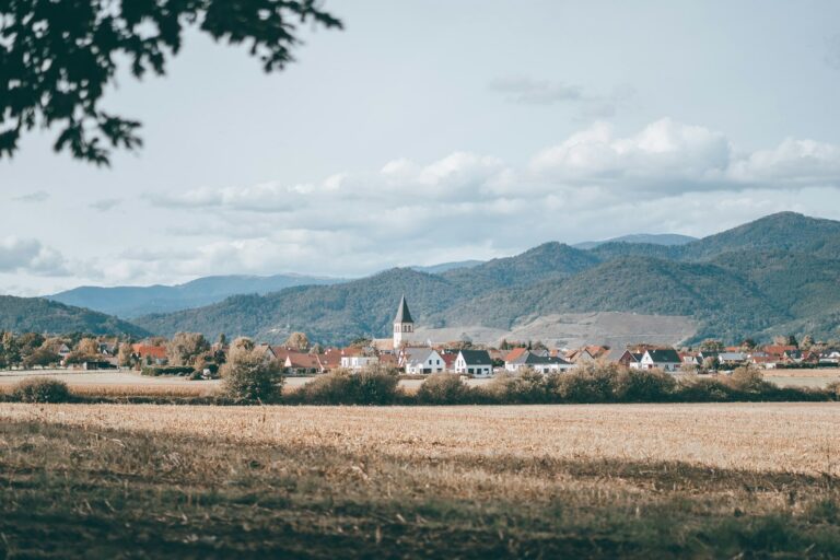 Village français et son clocher entre champs et montagnes en Alsace